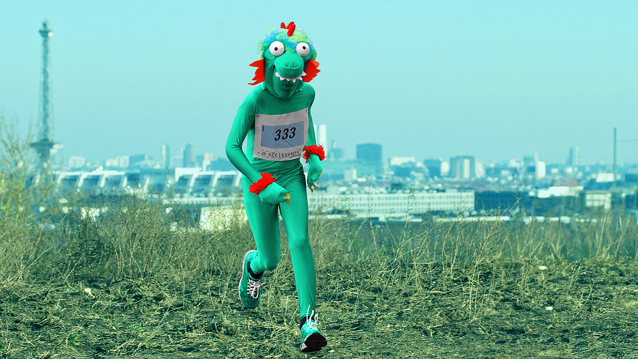 Berliner Silvesterlauf: Läufer im Drachenkostüm auf dem Drachenberg, im Hintergrund Funkturm und ICC @ SCC EVENTS / Tilo Wiedensohler