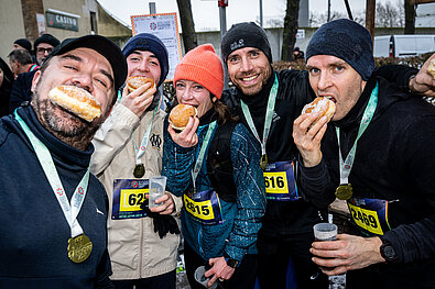 Teilnehmende feiern ihren Lauf im Ziel mit Pfannkuchen
